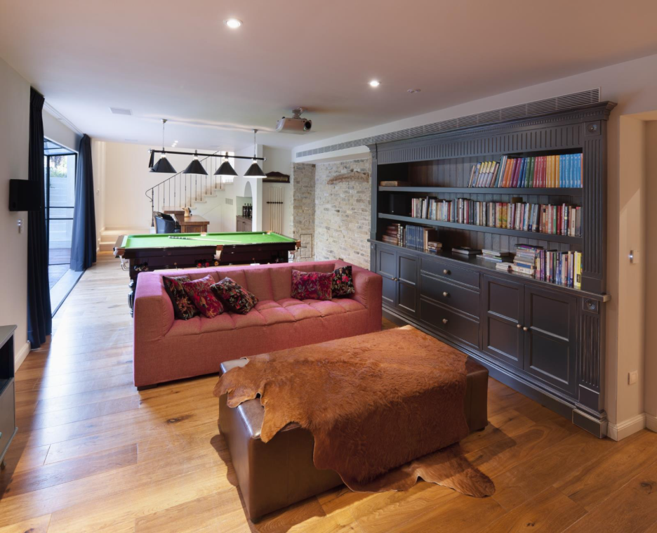 A finished basement with hardwood floors, a bookshelf, and a couch.